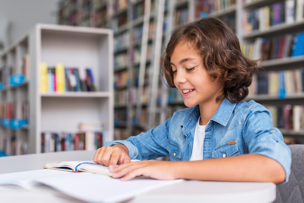 Foto gratuita ragazzino che fa i compiti in biblioteca