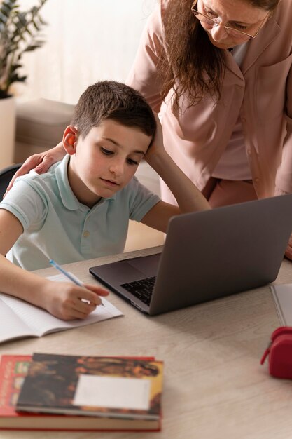 Little boy doing homework with his grandmother on laptop