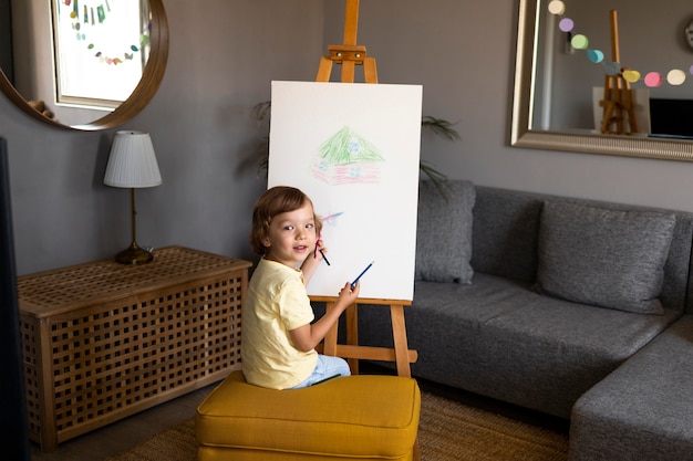 Бесплатное фото Маленький мальчик, рисующий на мольберте дома