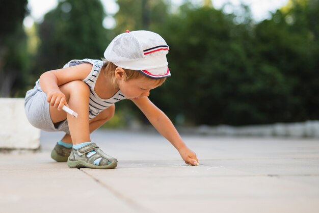 Little boy drawing with  chalk