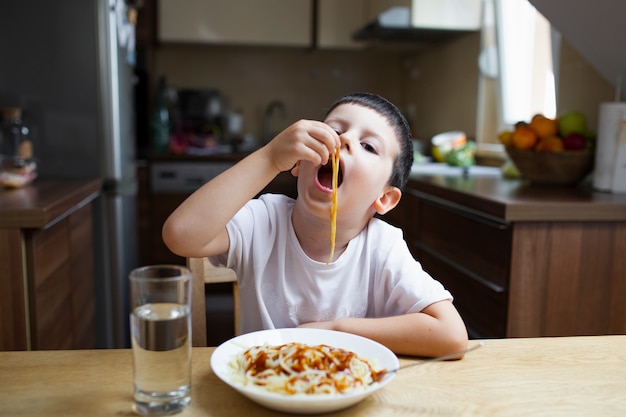 彼の手で食べる少年パスタ料理