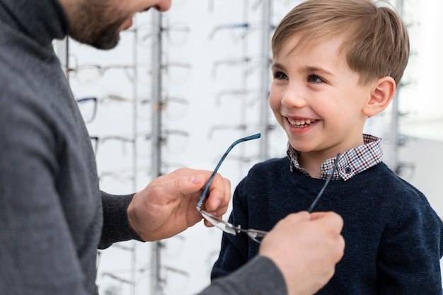 Little boy and father in store trying on glasses