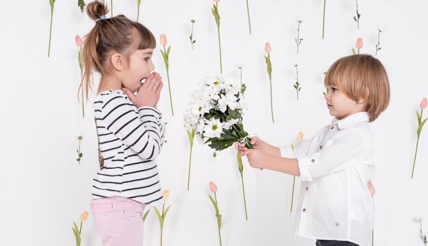 Little boy giving flowers to girl