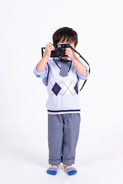 Маленький мальчик счастлив с камерой на белом