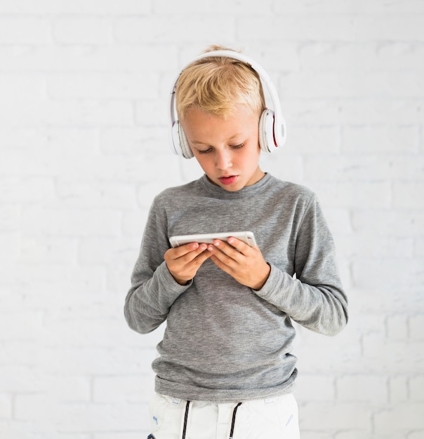 Little boy having fun with smartphone and earphones