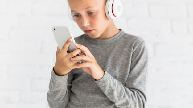 Little boy having fun with smartphone and earphones