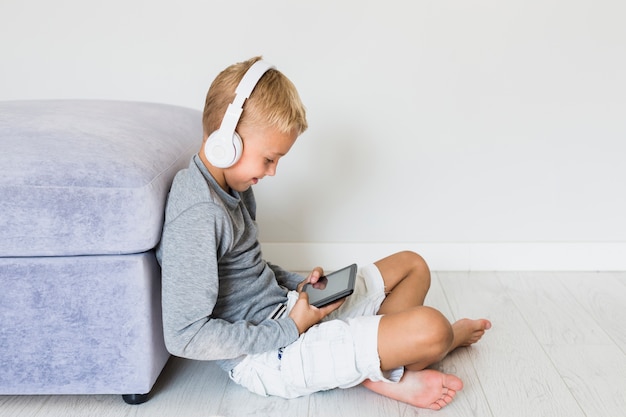 Free photo little boy having fun with tablet and earphones