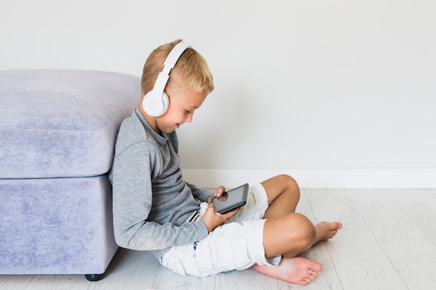 Little boy having fun with tablet and earphones