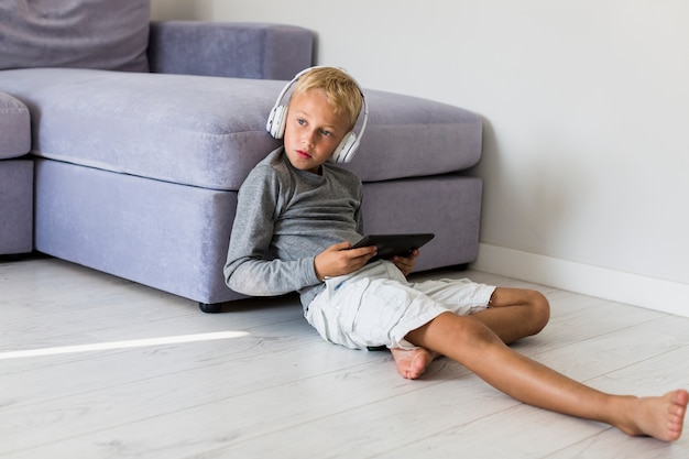 Little boy having fun with tablet and earphones