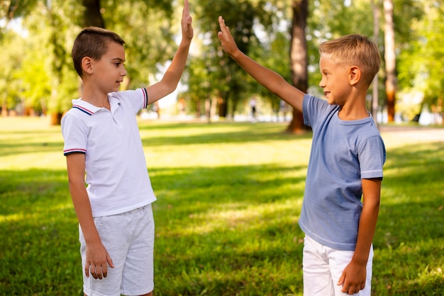 Foto gratuita alto fiving del ragazzino nel parco