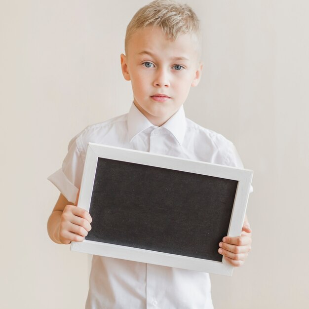 Little boy holding blackboard in studio