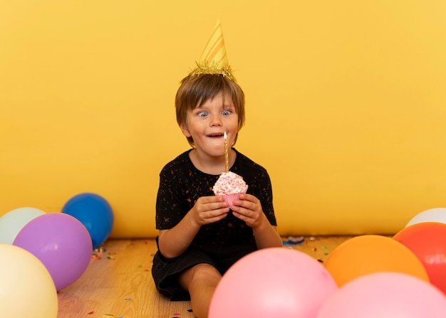 Little boy holding cupcake with candle