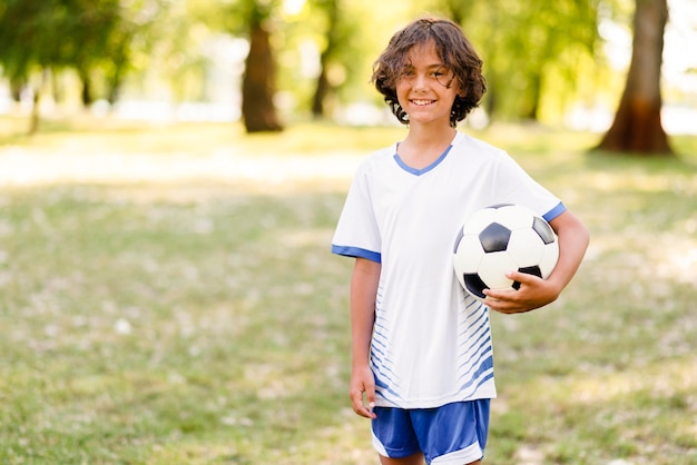 Маленький мальчик держит футбол с копией пространства