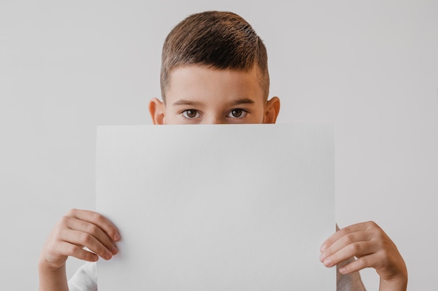 Free photo little boy holding a white paper