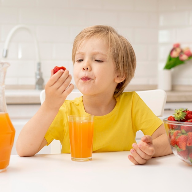 自宅で小さな男の子がイチゴを食べる