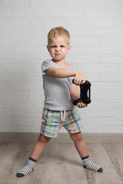 Free photo little boy at home playing with joystick