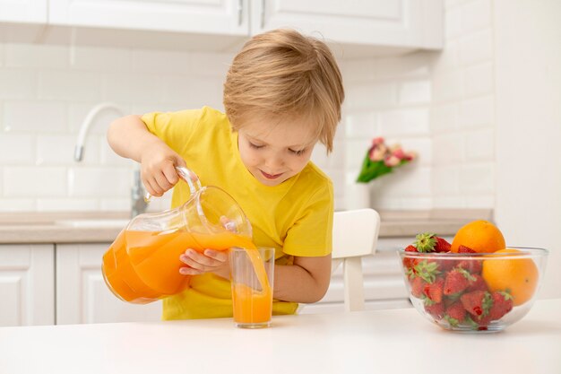 Маленький мальчик дома наливает сок