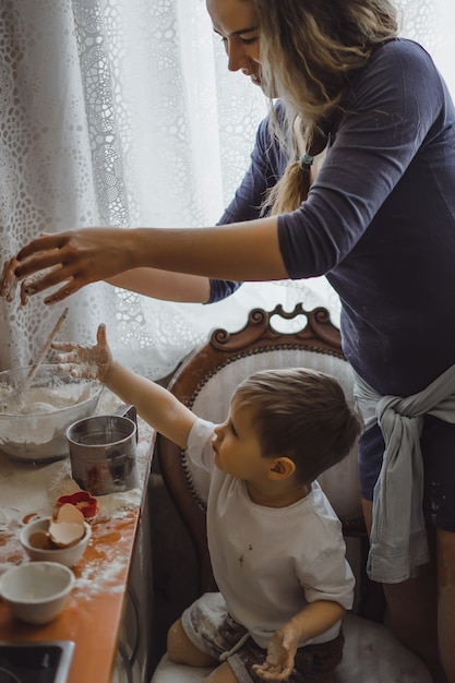 キッチンの小さな男の子は、お母さんが料理するのに役立ちます。子供は料理に関わっています。