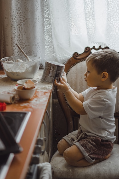 little boy in the kitchen helps mom to cook. the child is involved in cooking.