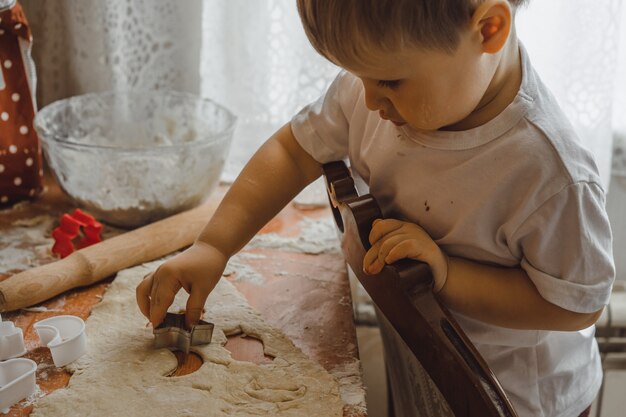 Маленький мальчик на кухне помогает маме готовить. ребенок участвует в приготовлении пищи.