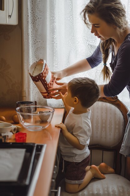 Маленький мальчик на кухне помогает маме готовить. ребенок участвует в приготовлении пищи.