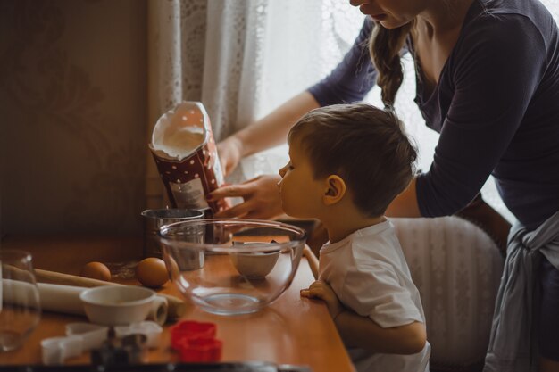 little boy in the kitchen helps mom to cook. the child is involved in cooking.