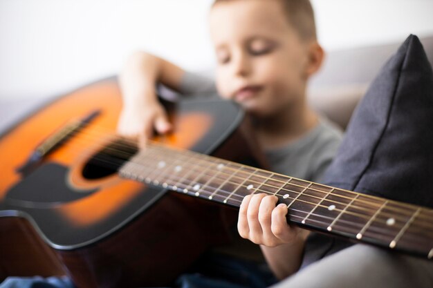 Little boy learning how to play guitar