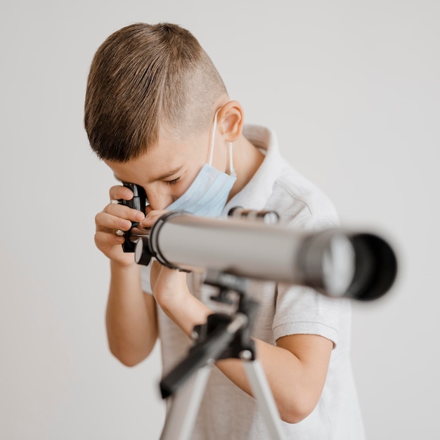 Маленький мальчик учится пользоваться телескопом