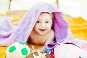 Free photo little boy lies under violet towel