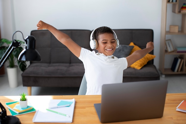 Free photo little boy listening to his teacher through headphones