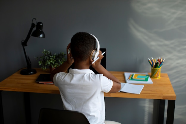 Free photo little boy listening to his teacher through headphones