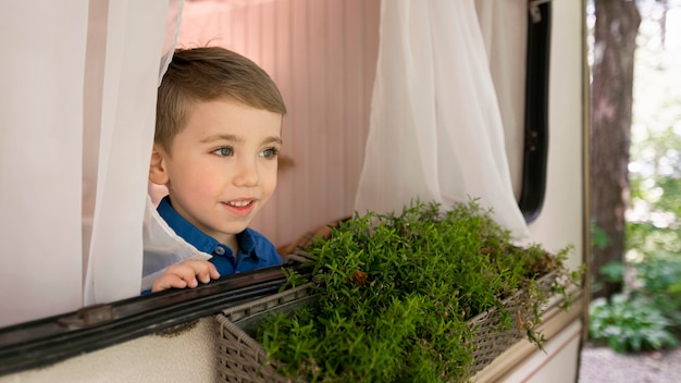 Little boy looking out of the window of his caravan