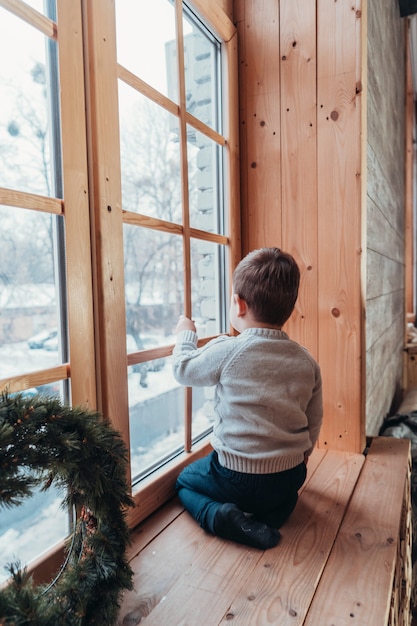 Little boy looking out the window holding his hand over the glass