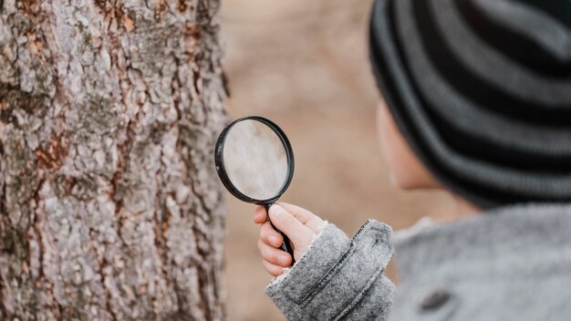 little boy looking through a magnifier outdoors