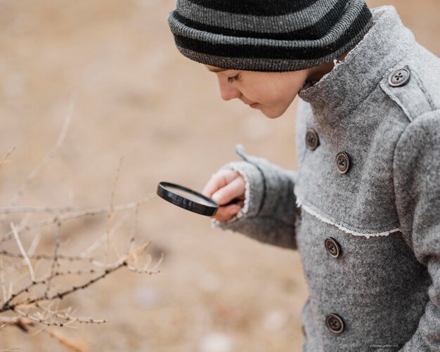 Little boy looking through a magnifier outside