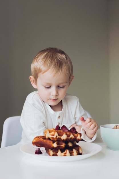 Free photo little boy looking at waffle