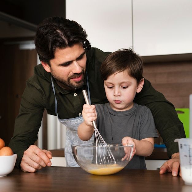 Little boy mixing eggs for dough