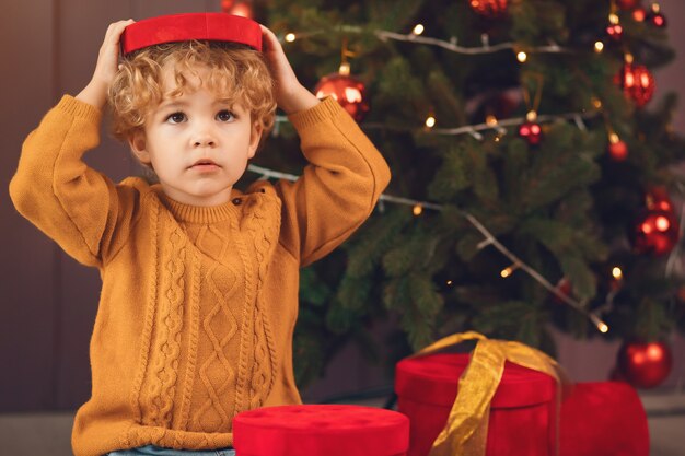 Little boy near christmas tree in a brown sweater