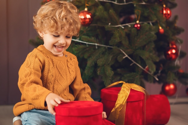 茶色のセーターでクリスマスツリーの近くの小さな男の子