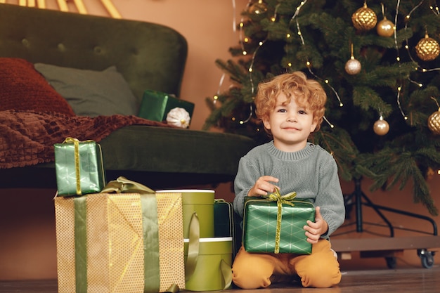 灰色のセーターでクリスマスツリーの近くの小さな男の子