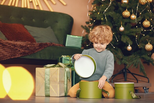 Little boy near christmas tree in a gray sweater