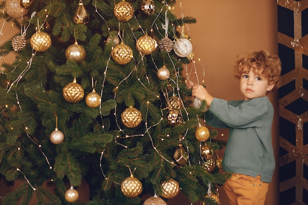 Little boy near christmas tree in a gray sweater