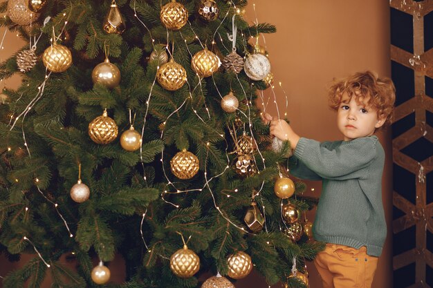 灰色のセーターでクリスマスツリーの近くの小さな男の子