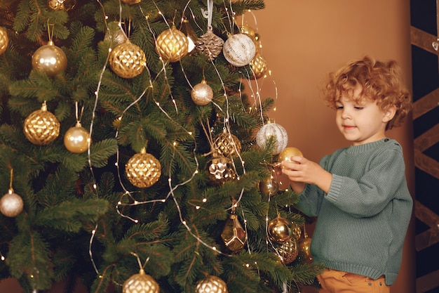 Little boy near christmas tree in a gray sweater
