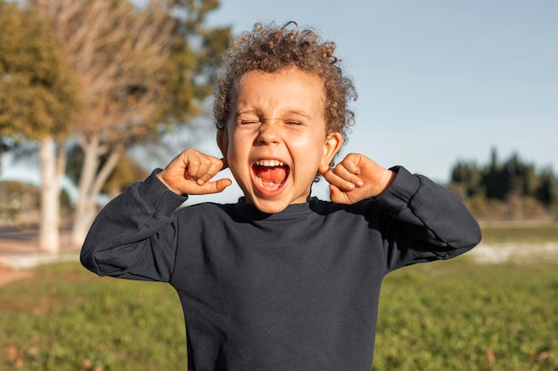 Little boy outdoors covering his ears