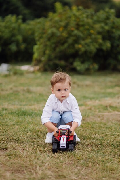 Игра маленького мальчика с игрушечным автомобилем на траве