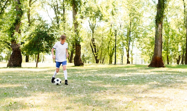 Free photo little boy playing football alone with copy space