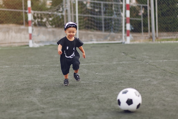 Little boy playing football in a sports ground