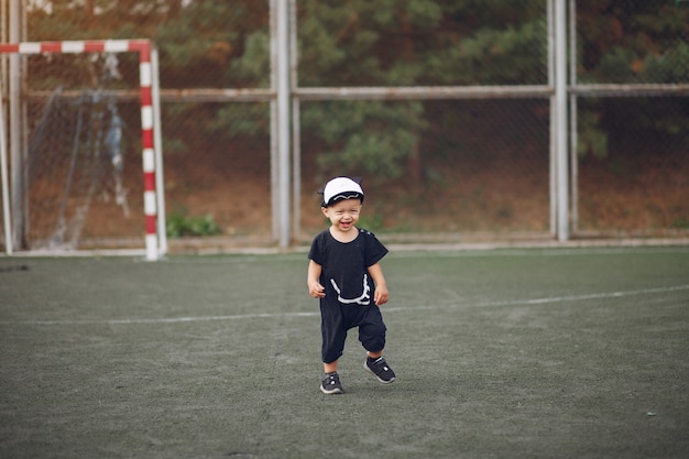 Маленький мальчик играет в футбол на спортивной площадке