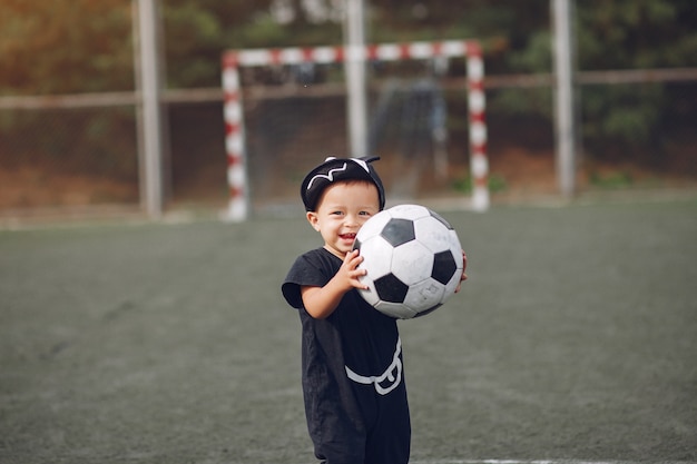 Little boy playing football in a sports ground